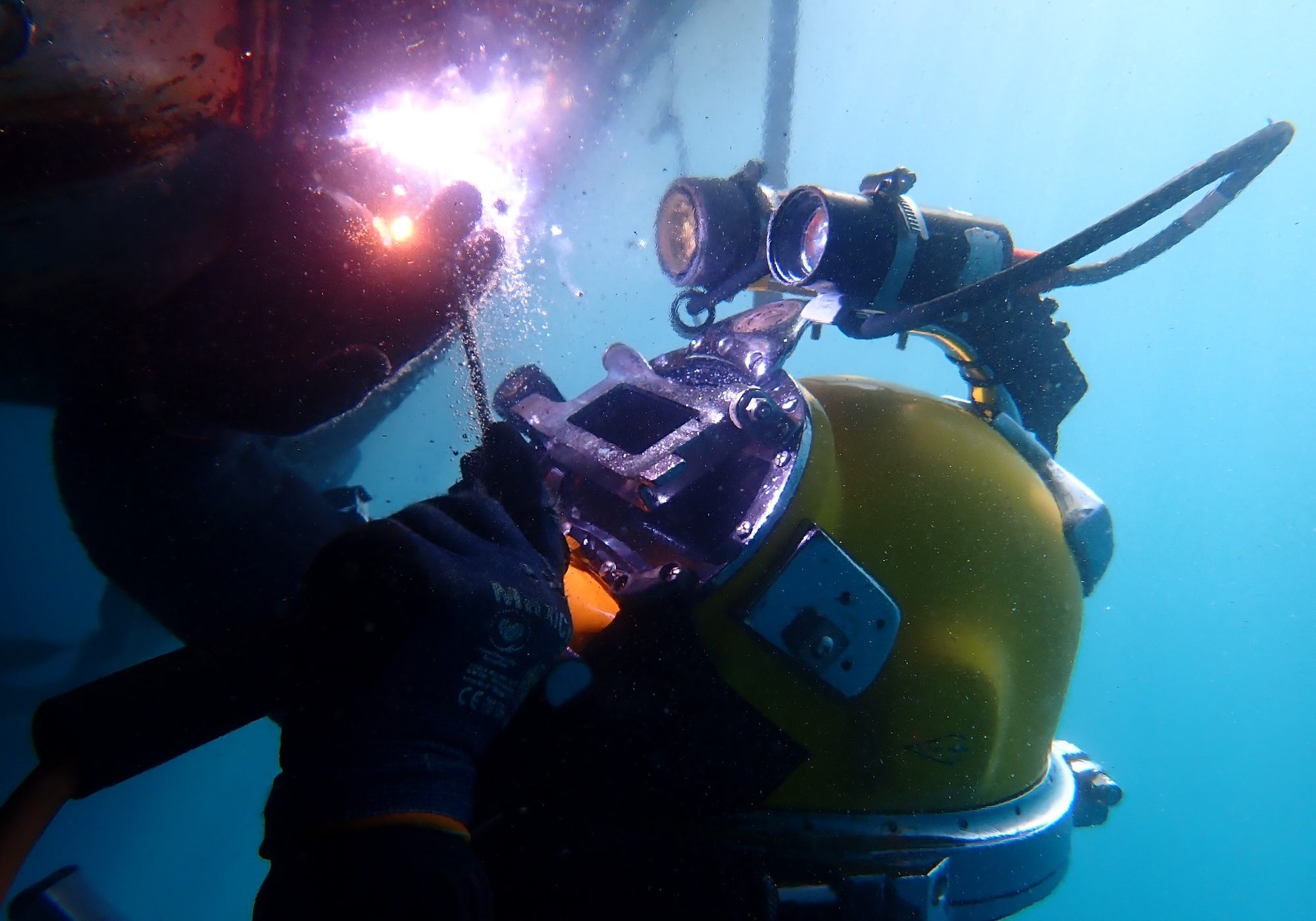 commercial diver wearing yellow diving helmet and diving gear working underwater